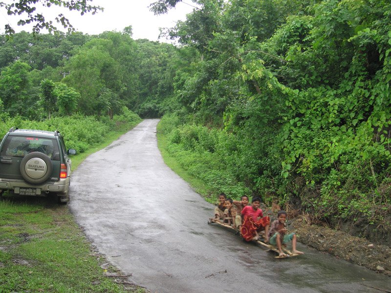 a bunch of screaming kids on two boards with wheels roll down the hill past us
