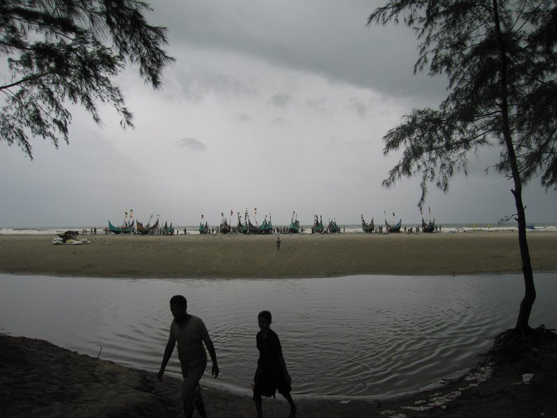 a couple villagers coming from the fishing boats lined up on the beach
