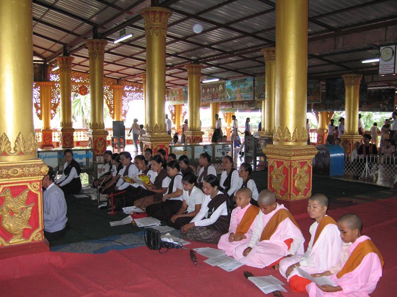 female monks and schoolgirls praying at the temple on full moon day
