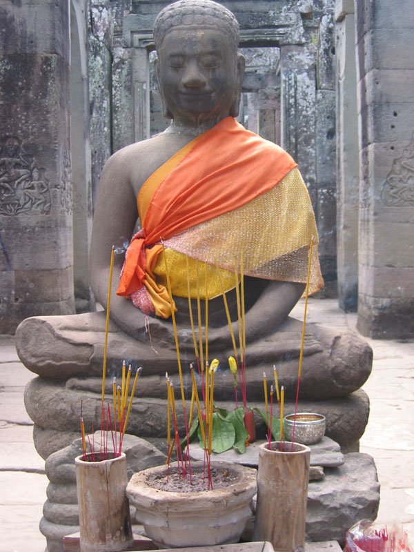 incense and offerings at the foot of a Buddha at the Bayon
